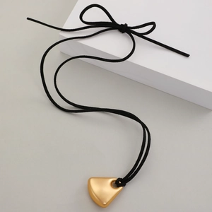 Détail du pendentif bouclier doré mat sur cordon en suédine noire avec un noeud