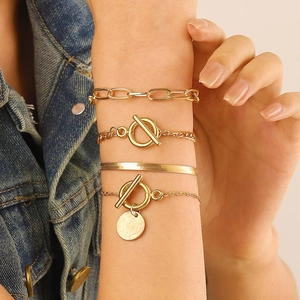 Gros plan d'un ensemble de 4 bracelets dorés avec chaîne serpent et fermoir OT sur poignet