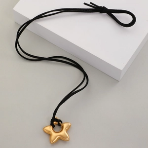 Détail d'un collier pendentif étoile dorée mate avec cordon noir et centre évidé