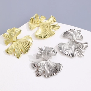 Detailed view of textured ginkgo leaf earrings in gold and silver metal finishes
