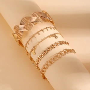 Détail d'un ensemble de cinq bracelets dorés à maille serpent avec trèfle et pendentif cœur