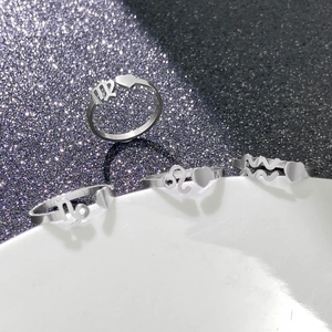 Detailed view of silver zodiac heart rings on a ceramic plate with glitter background