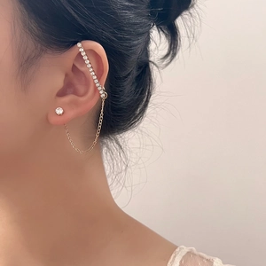 Elegante pendiente de cadena dorada con manguito y brillantes tachuelas de circón