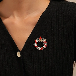 Detailed view of a Christmas wreath brooch with red and green enamel on a black sweater