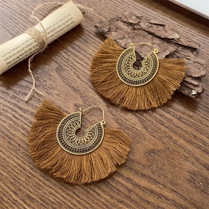 Detalle de pendientes bohemios en abanico con filigrana de bronce y flecos de seda marrón