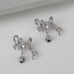 Detailaufnahme silberner Liquid-Metal-Ohrringe mit schwarzen Tropfenanhängern