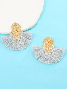 Detalle de pendientes bohemios en forma de abanico con flecos y discos dorados con textura
