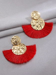 Detalle de pendientes de flecos rojos en forma de abanico con metal dorado martillado