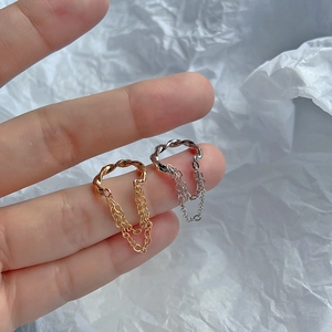 Detail von Gold- und Silberwellenringen mit Doppelmetallketten am Finger des Modells