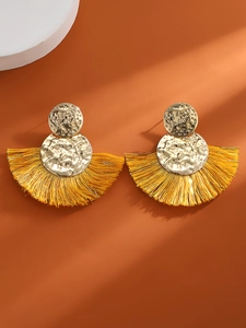 Vista macro de pendientes de abanico dorados con metal martillado y borlas de flecos amarillos