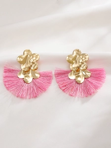 Detalle de los pendientes de flores doradas y borlas de seda rosa en forma de abanico