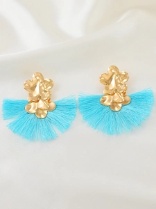 Detalle de pendientes dorados en forma de abanico con borlas de seda azul cielo sobre seda