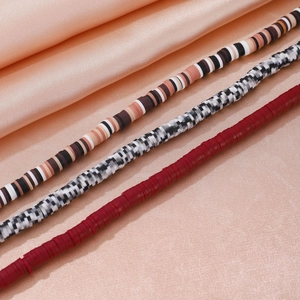 Details von bunten Boho-Heishi-Perlenketten auf elegantem hautfarbenem Seidenstoff