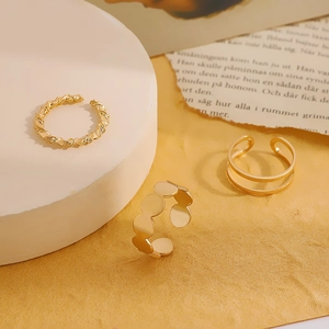 Detail showing three gold-tone minimalist open rings with twist and circular patterns