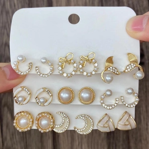 Set di nove paia di orecchini vintage in lega dorata con perle e cristalli su carta