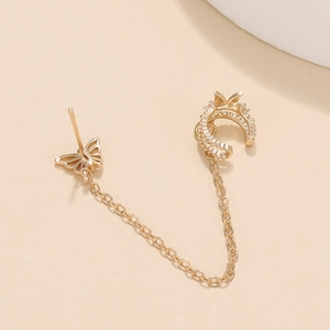 Detail von goldenem Schmetterlingsstecker mit Quastenkette und Zirkon-Ohrmanschette
