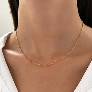 Detail van een minimalistische gouden kabelketting gedragen door een vrouwelijk model