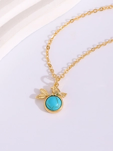 Detail of gold bird pendant with turquoise stone on a minimalist chain necklace