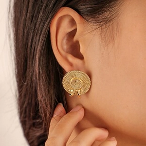 Close-up of golden straw hat stud earring with bow detail worn by a model