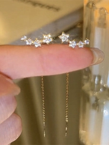 Detail eines goldenen langen Quasten-Ohrrings mit glitzernden Sternen aus Zirkonia