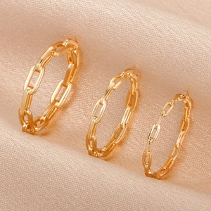 Macro shot of three gold-plated chain link rings on elegant champagne silk background