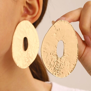 Macro shot of large vintage hollow golden earrings with textured hammered finish detail