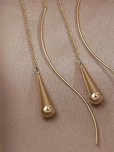 Detaillierte Makroansicht langer goldener Kettenohrringe mit glatten polierten Tropfen