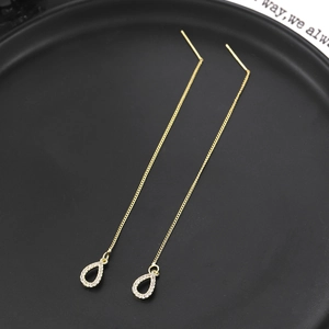 Makro-Detail goldener Durchzieher-Ohrringe mit Zirkonia-Anhängern in Tropfenform