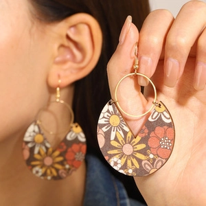 Detail of wooden bohemian floral earrings showing retro daisy patterns and ear hook design