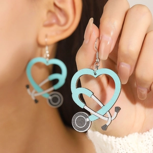 Detail view of heart-shaped stethoscope wooden earrings in mint blue on a model