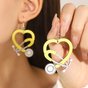 Detail of creative heart-shaped stethoscope wooden earrings worn by a model in yellow and white