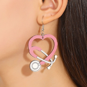 Close-up of pink and white heart-shaped stethoscope wooden earrings worn by a model