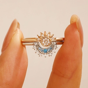 Close-up of rose gold sun and moon stacking rings set with shimmering blue and white zircons