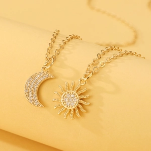 Detail van gouden zon- en maanhangers met pavé-gezette zirkonia aan een fijne kruisketting