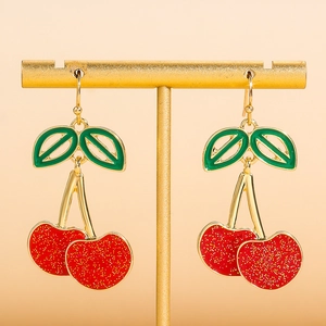 Sparkling red cherry acrylic drop earrings with green leaves on a golden stand
