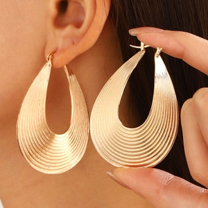 Exaggerated large teardrop earrings with textured gold stripes and a retro geometric design