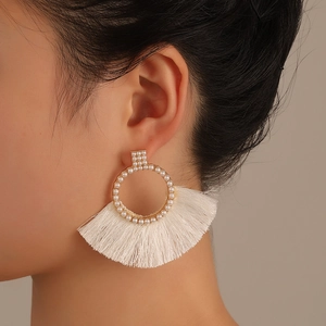 Detailed view of bohemian white fan tassel earrings with pearls on a female model