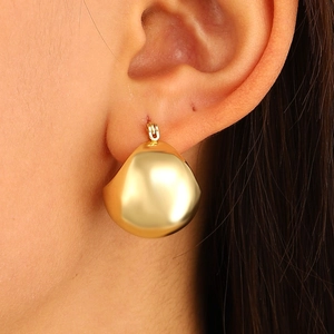 Macro shot of stylish gold water drop earrings with a polished mirror finish on model