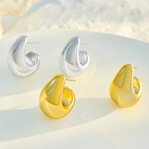 Macro detail of minimalist hollow water drop earrings in polished gold and silver finishes
