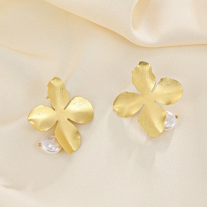 Golden brushed flower earrings with white pearl detail on champagne satin fabric