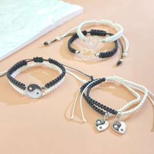 Detalle de pulseras de amistad hechas a mano con dijes de corazón y de yin yang