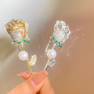 Close-up of elegant rose brooches with rhinestones and pearls in gold and silver