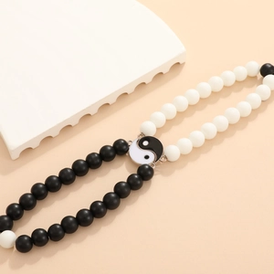 Detalle de pulseras para parejas con cuentas mate en blanco y negro y dijes de Yin-Yang