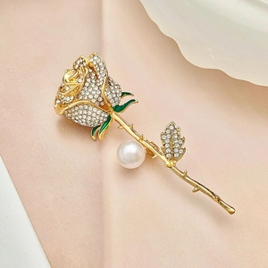 Macro shot of elegant rose brooch with white rhinestones and green enamel details