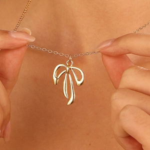 Détail d'un collier avec pendentif nœud doré poli sur un modèle montrant l'élégante chaîne