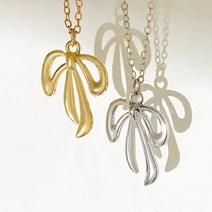 Detailansicht eleganter goldener und silberner Metallschleifen-Anhänger mit Seidenstruktur