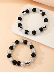 Detalle de pulseras de cuentas con dijes de Yin Yang en cordón elástico para parejas