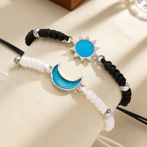 Detalle de pulseras de pareja tejidas con sol y luna y esmalte azul en un soporte