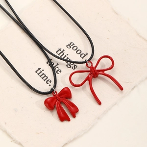 Primer plano de dos colgantes de lazo rojo metálico con cadena de cordón negro