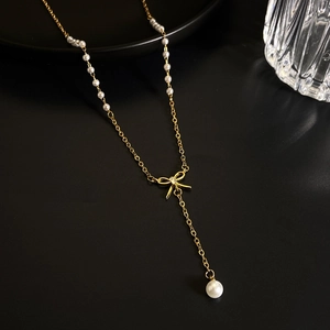 Detail der goldenen Schleifen-Halskette mit eleganten weißen Perlen und funkelndem Diamanten